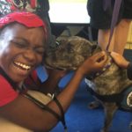 A woman petting a pit bull and smiling