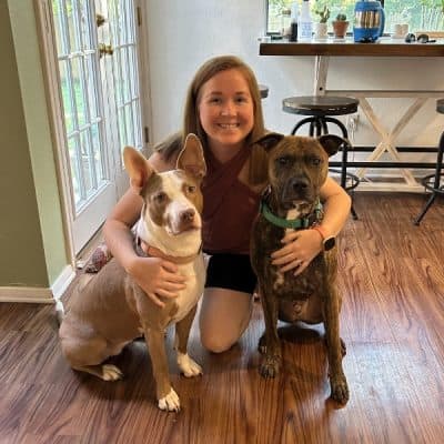 Woman kneeling in a house with two dogs in front of her.