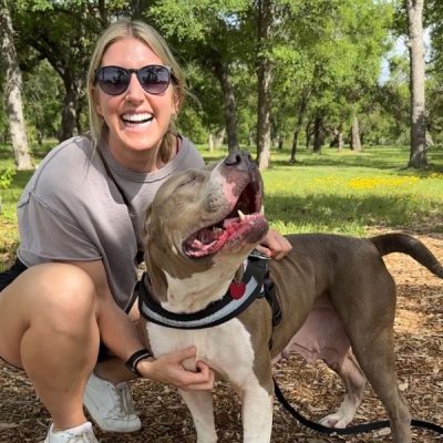 Woman smiling with a gray and white pit bull outdoors