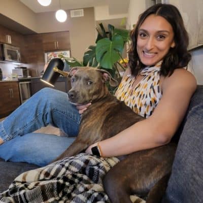 Woman sitting on a couch with a pitbull dog.